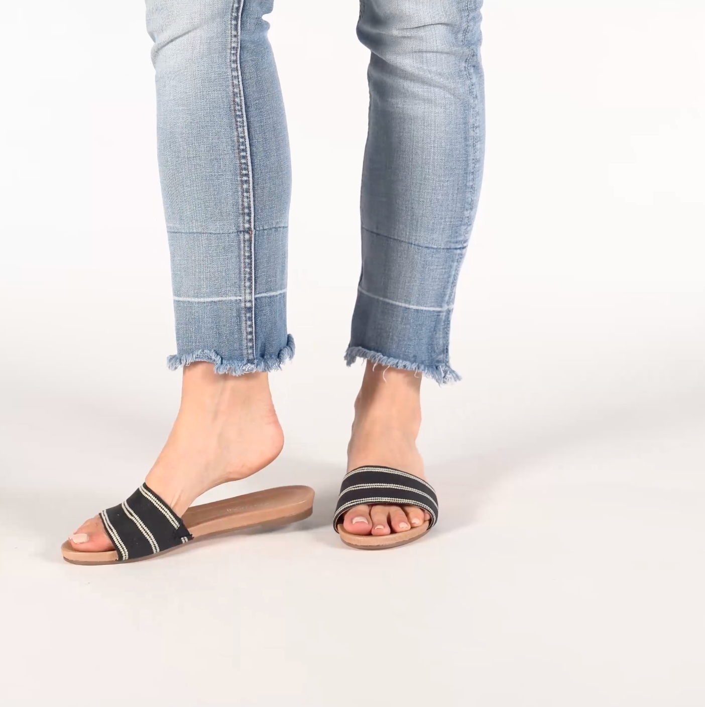 woman walking in black hari mari sydney slide sandals in jeans on white background